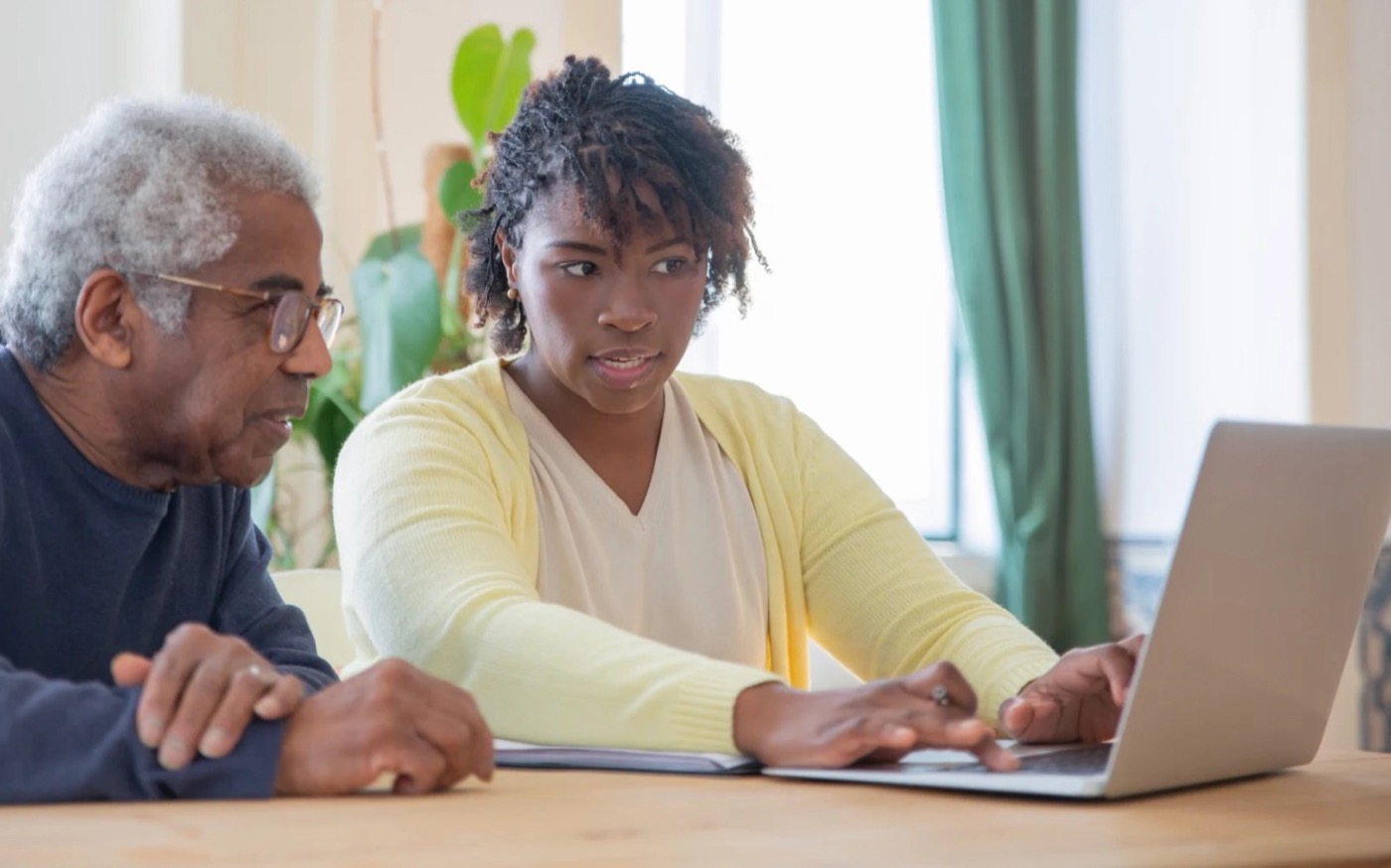 A woman at a laptop beside her father, working through something together